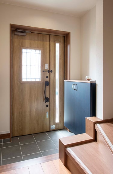 玄関収納には、ブルーグレーオークの｢コンポリア｣を採用。ネイビーの室内扉とデザインを合わせて。