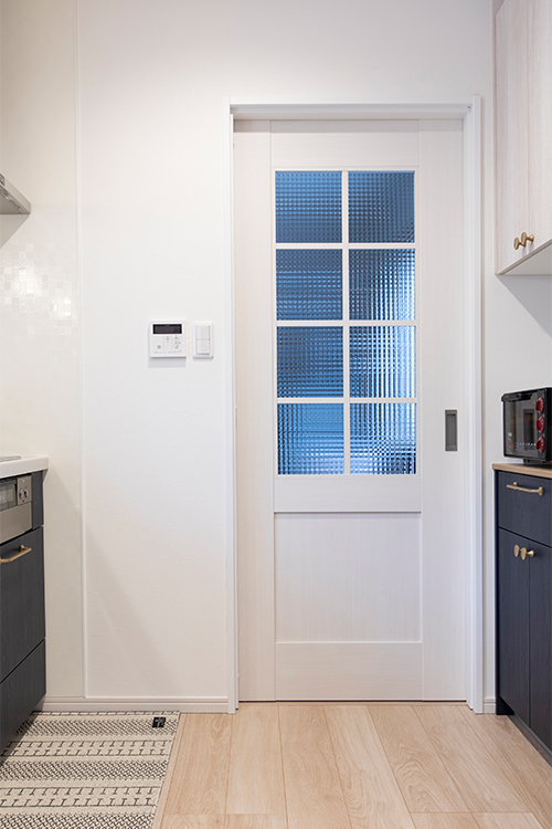 写真：キッチンから洗面所へ続く引戸は光の差し込むドアを採用。