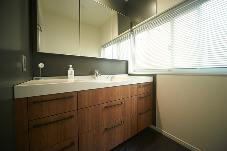 写真：ゆっくり使える広々とした洗面室は、壁面の一部を黒にしてシックな印象に。