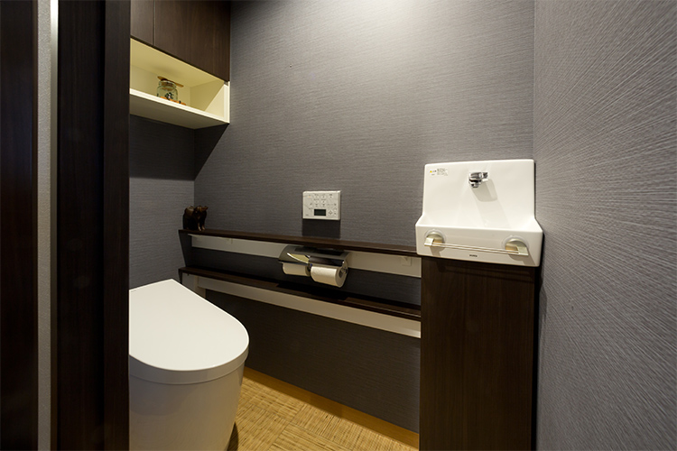 写真：グレーの壁紙と籐素材の床で和風に統一されたトイレ空間