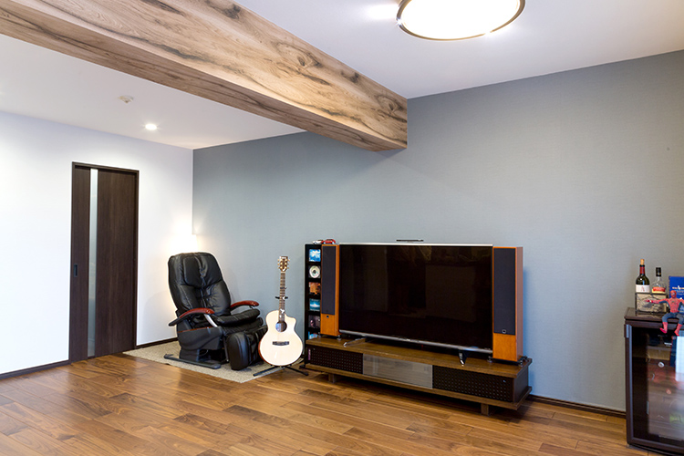 写真：広々としたLDK空間。音響セットを整えたテレビとギターなどが置かれている。